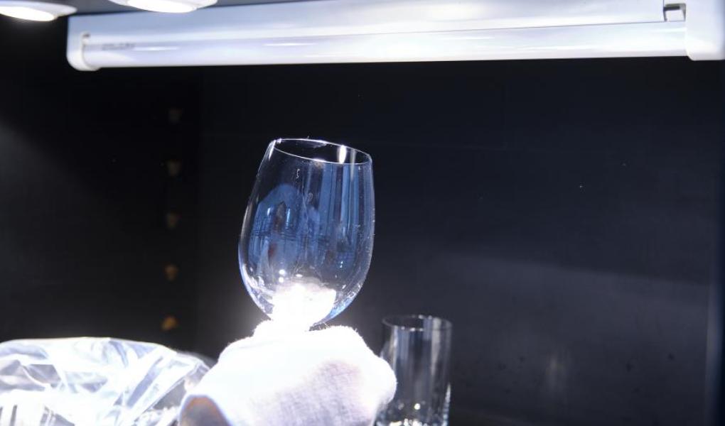 Grå film på glass og bestikk etter servise vurderes i laboratoriets lyskammer. Foto: Tobias Meyer